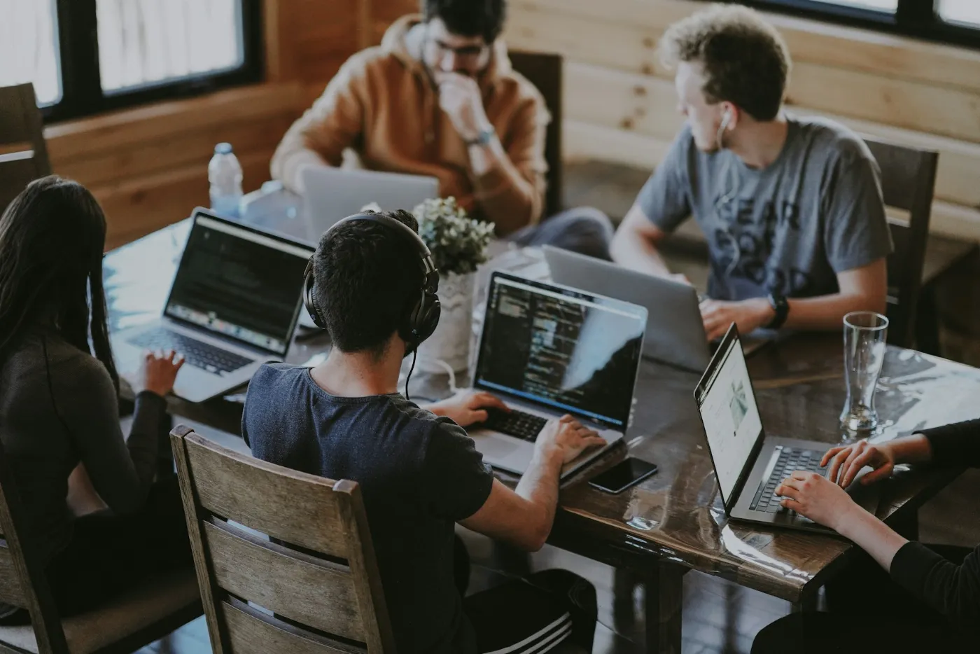 Software developers working on laptops around a wooden table