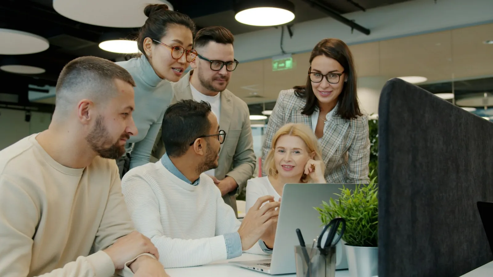 Colleagues gathered around a laptop in a bright office